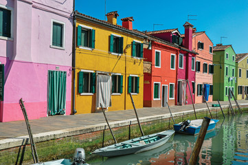 Fototapeta na wymiar Panoramic view of colorful buildings and boats in front of a canal at Burano, a gracious little town full of canals, near Venice. In the Veneto region, northern Italy
