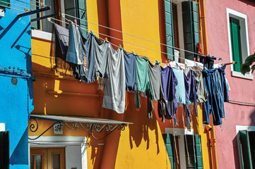 Close-up of windows on colorful walls and clothes hanging on sunny day in Burano, a gracious little town full of canals, near Venice. Veneto region, northern Italy