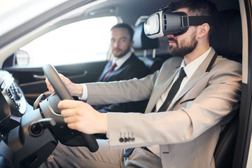 Side view portrait of handsome bearded  businessman wearing VR headset sitting behind wheel of luxury car, modern technology concept