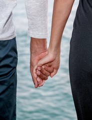 female hand in a man`s hand, on a background of the sea, summer, love
