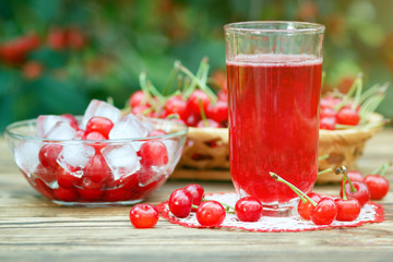 Glass of stewed fruit cherry compote on wooden table in garden
