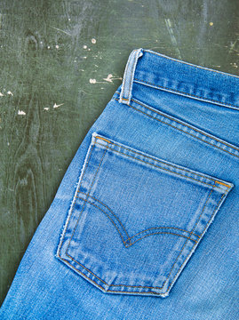 Blue jeans pocket on old wooden background. Top view