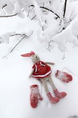A toy rabbit walks in a snowy forest