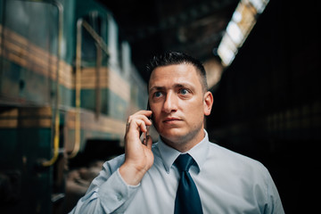 Train driver in front of locomotive call up someone with concerned, worried face