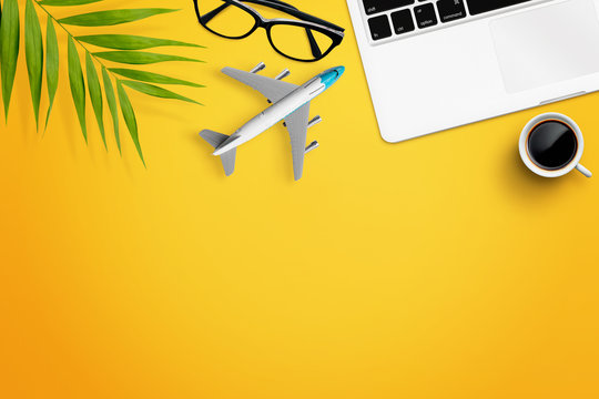 Laptop, coffee, glasses, airplane and green leaf on yellow background. Free space for text, icons, wtc. Travel concept, flat lay
