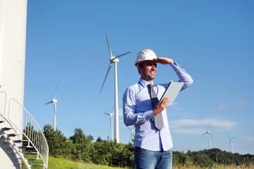 An engineer controls the functioning of wind turbines that run thanks to the force of the wind and generate electricity sustainably to the planet. Concept of: renewable energy, love for nature 