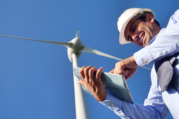 An engineer controls the functioning of wind turbines that run thanks to the force of the wind and...