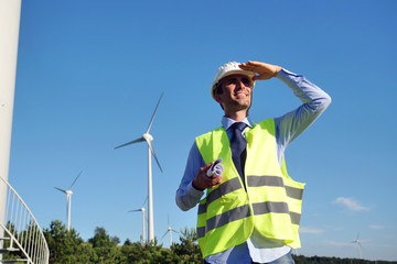 An engineer controls the functioning of wind turbines that run thanks to the force of the wind and...