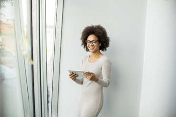 Young African American businesswoman standing wirth tablet in the office by window