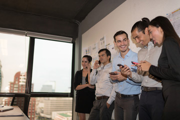 Photo young businessman crew working till evening down light with new startup project. They are standing and use smartphone on break. Analysis Business Brainstorming Corporate Smart Concept.