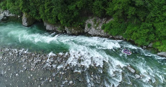 3 rafts descend an alpine river between rapids and rocks. White water rafting on Sesia river, Piedmont, Italy.