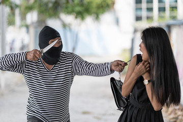 A robber is threatening a woman by a knife. He try to pull a bag from a woman. Selective focus at a...