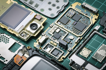 electronic parts of old mobile phone with semiconductor parts and precious metals close-up on green...