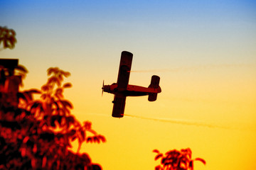 Biplane flying in the vibrant sunset