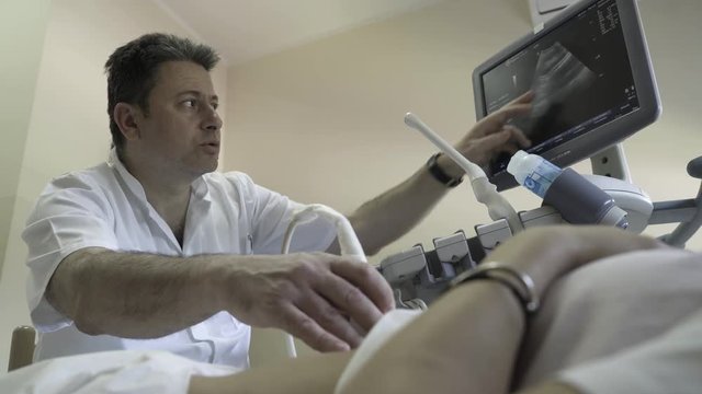 Doctor gynecologist performing examination with ultrasound on gynecology ward in hospital, woman on medical review, hand close up, low angle view, female patient lying in ambulance room, health care