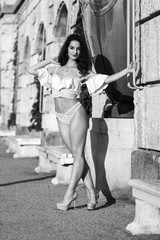 Lifestyle portrait of a brunette woman posing in white lingerie on street