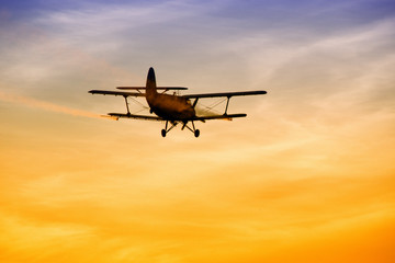 Biplane flying in vibrant sunset