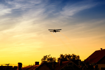 Biplane flying over trees in vibrant sunset