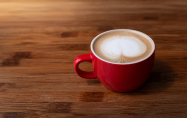 A red cup of Latte coffee on wooden table, close up
