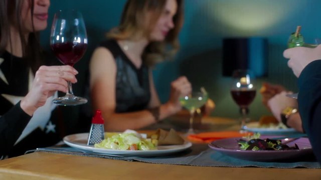 Friends clinks glasses with vine and cocktails at restaurant