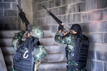 Fototapeta premium Asian army soldier with rifle and machine gun moving patrol around building. selective focus at gun of human right side