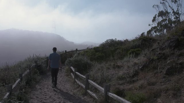 Man walking in San Fransisco Grandview Park, with Foggy Sutro Tower 