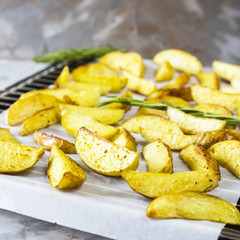 Baked potatoes on a baking sheet with pieces of spices and rosemary. Homemade cooking in the kitchen