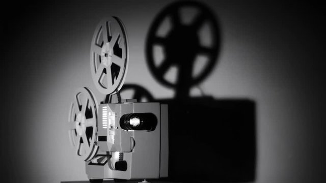 Movie projector 8-mm film. The film projector is loaded with a film and a film is shown.	