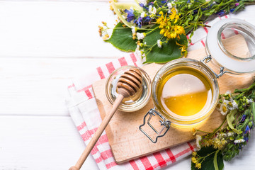 Honey  in a jar with wild herbs on white