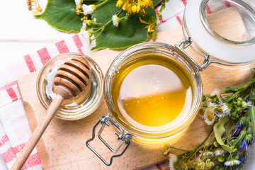 Honey  in a jar with wild herbs on white
