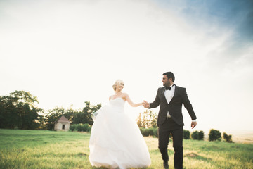 Stylish couple of happy newlyweds walking in the park on their wedding day with bouquet