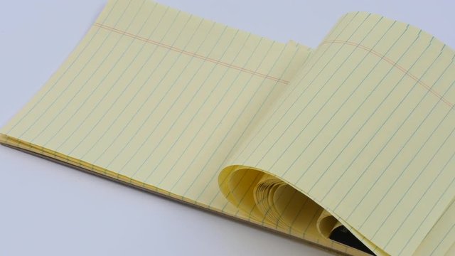 Panning Lined yellow note pad in wind