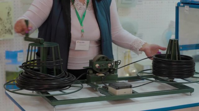 Dealer turns spool of electric wire extension cord with long cable