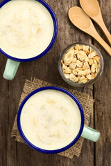 Refreshing rhubarb and yogurt smoothie in enamel cups with homemade oatmeal and almond granola on the side (Selective Focus, Focus on the drinks and the granola)