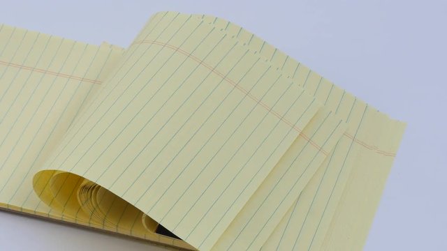 Panning Lined yellow note pad in wind