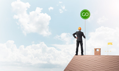 Obraz premium Businessman in suit on house top with ecology concept signboard. Mixed media