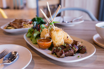 Grilled sticky rice with egg served with grilled diced steak with salad.