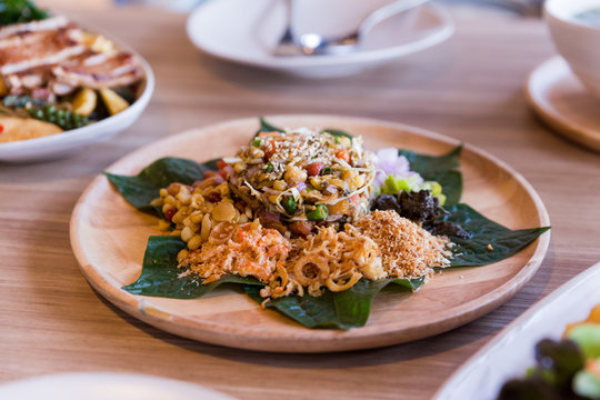 Lahpet is Burmese Tea Leaf Salad served with deep fried garlic, peanut, white sesame, dried shrimp, ginger and roasted coconut.