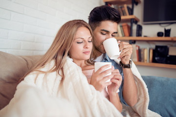 Young couple relaxing on a sofa and drink coffee