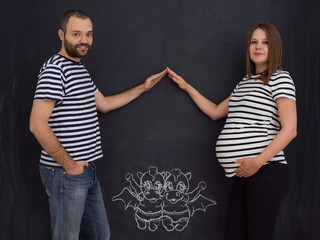 pregnant couple drawing their imaginations on chalk board