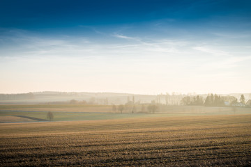 Nebel und blauer Himmel über einem Feld in Sachsen