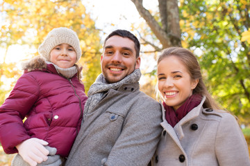 family, season and people concept - happy mother, father and little daughter walking at autumn park