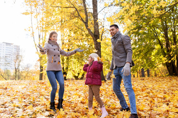 Fototapeta premium family, season and people concept - happy mother, father and little daughter playing with autumn leaves at park