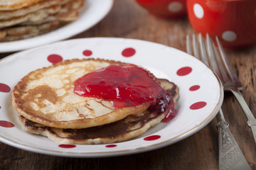 Pancakes with red currant jam and red coffee cups