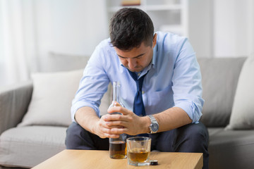 alcoholism, alcohol addiction and people concept - male alcoholic with bottle and drinking whiskey at home - obrazy, fototapety, plakaty