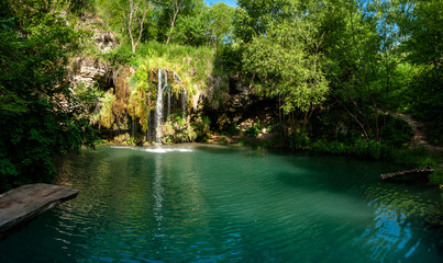 Naklejka premium Waterfall and a beautiful lagoon lake for relaxing in the summer forest.