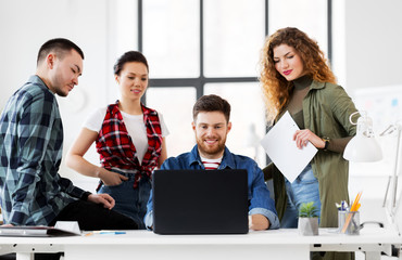 business, technology and people concept - happy creative team with laptop computer working at office