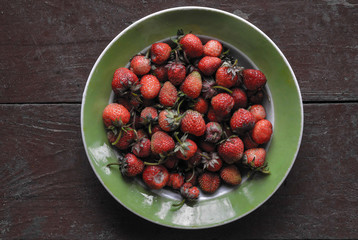 Strawberries in a plate on a wooden background