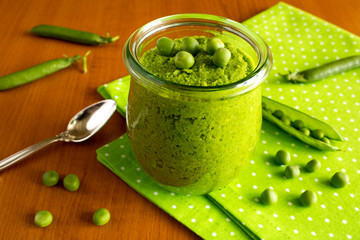 Children's puree with peas  in the glass jar on the green napkin