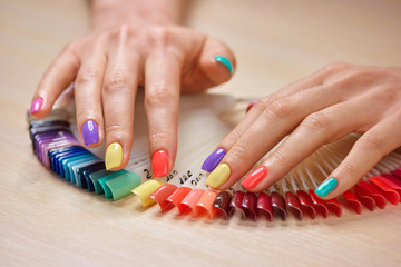 Obraz na płótnie Canvas Summer colorful manicure on female hands. Beautiful caucasian lady hands with stylish summer manicure. Professional nails studio.